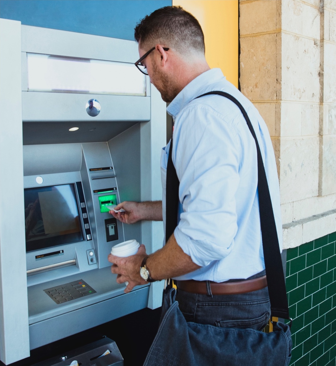 a man with a shoulder bag at the ATM