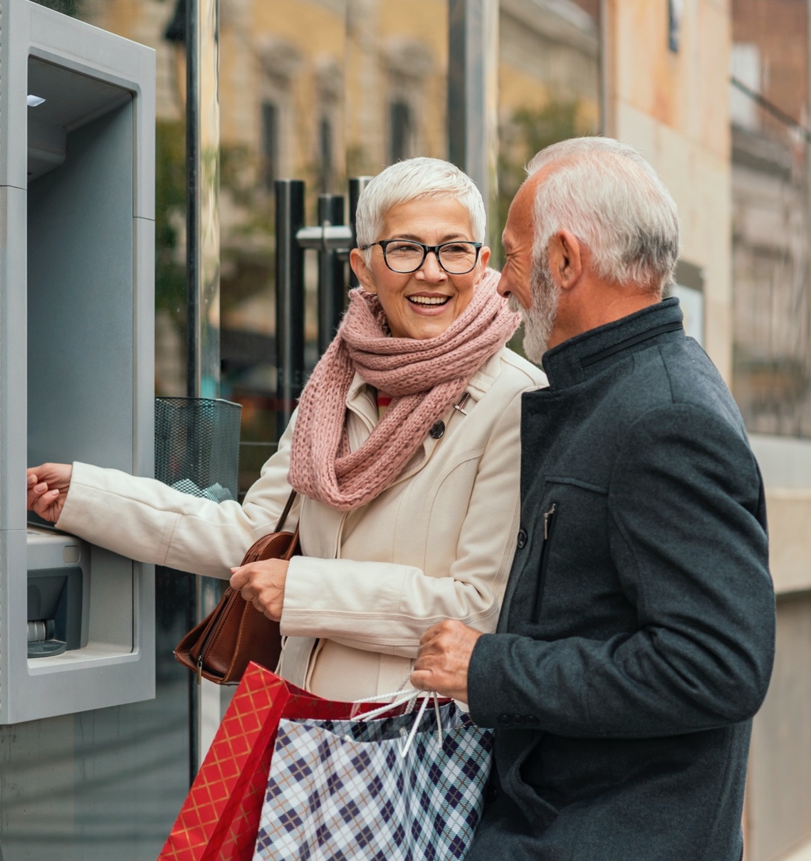 older couple laughing while using ATM